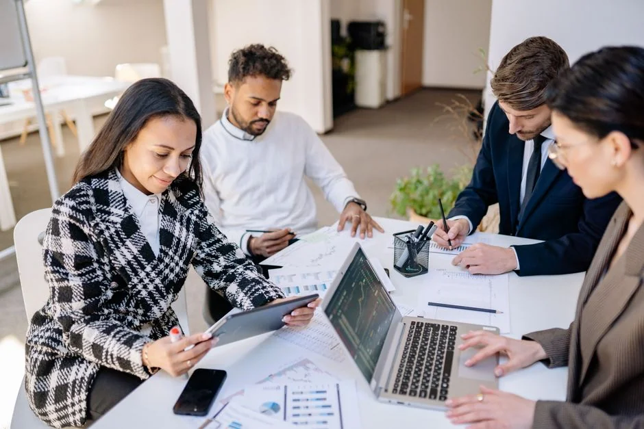 Team che collabora sull'analisi dei dati finanziari con grafici su laptop e documenti.